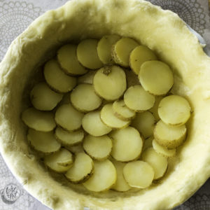 Looking into pie crust at the first layer of potatoes.