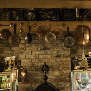 Old copper pots and pans hanging from a wooden beam.